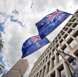 Low angle shot of Australian flags waving from a Government Building against a cloudy sky