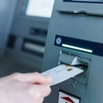 Person insert card to automated teller machine. Cashing non-cash money by individual.