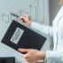 Cropped view of lawyer holding book with intellectual property lettering and pointing with pen at