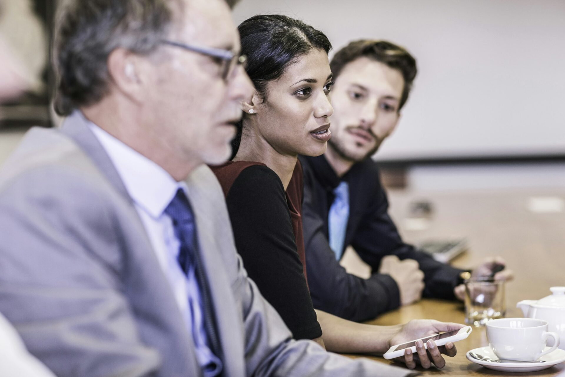 Businesswoman and businessmen listening in board meeting