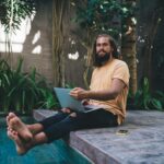Portrait of Caucasian programmer with laptop keeping freelance digital nomad lifestyle