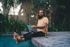 Portrait of Caucasian programmer with laptop keeping freelance digital nomad lifestyle