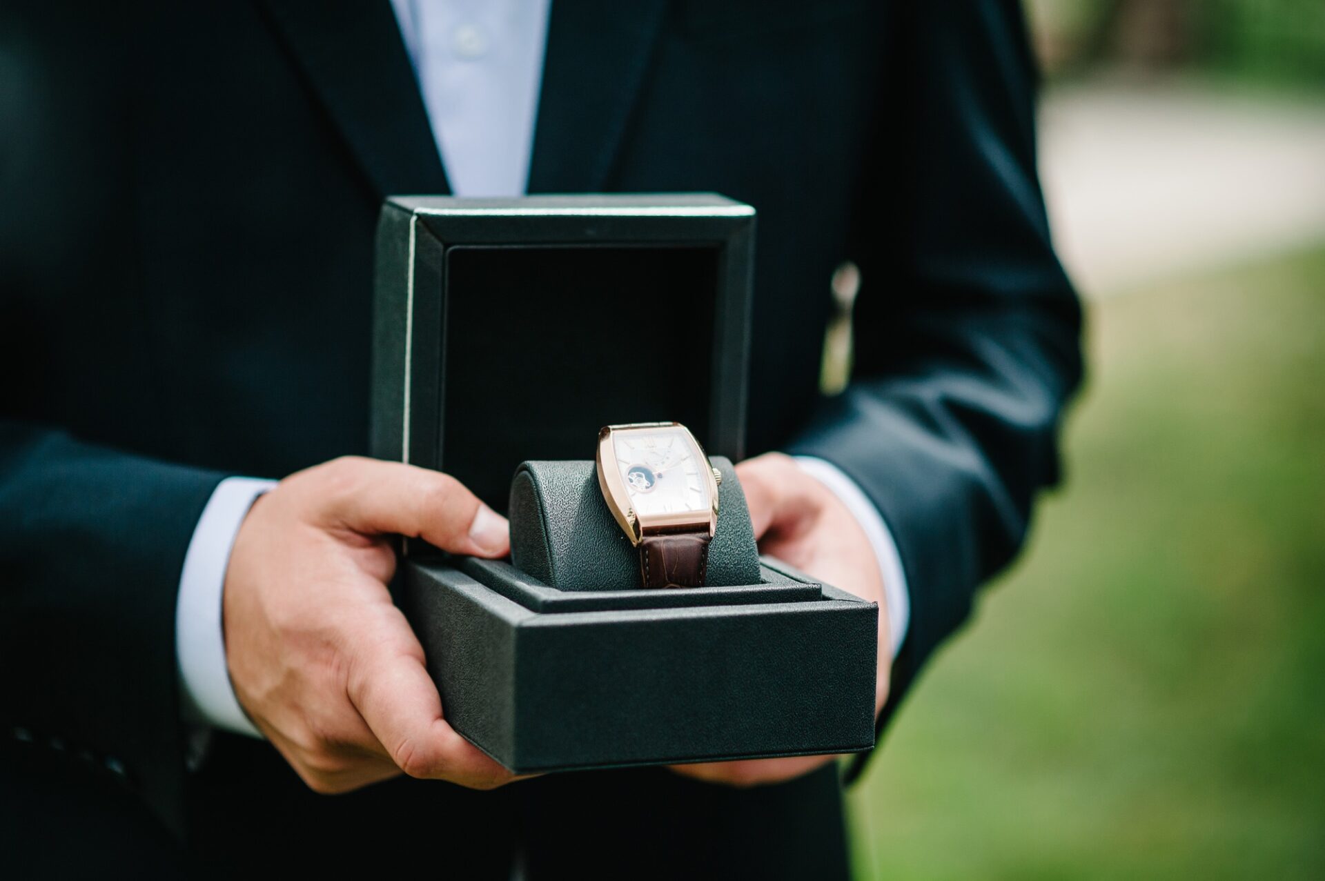 Cropped shot of a man wearing elegant suit and hold wrist watch. Man hand with elegant expensive