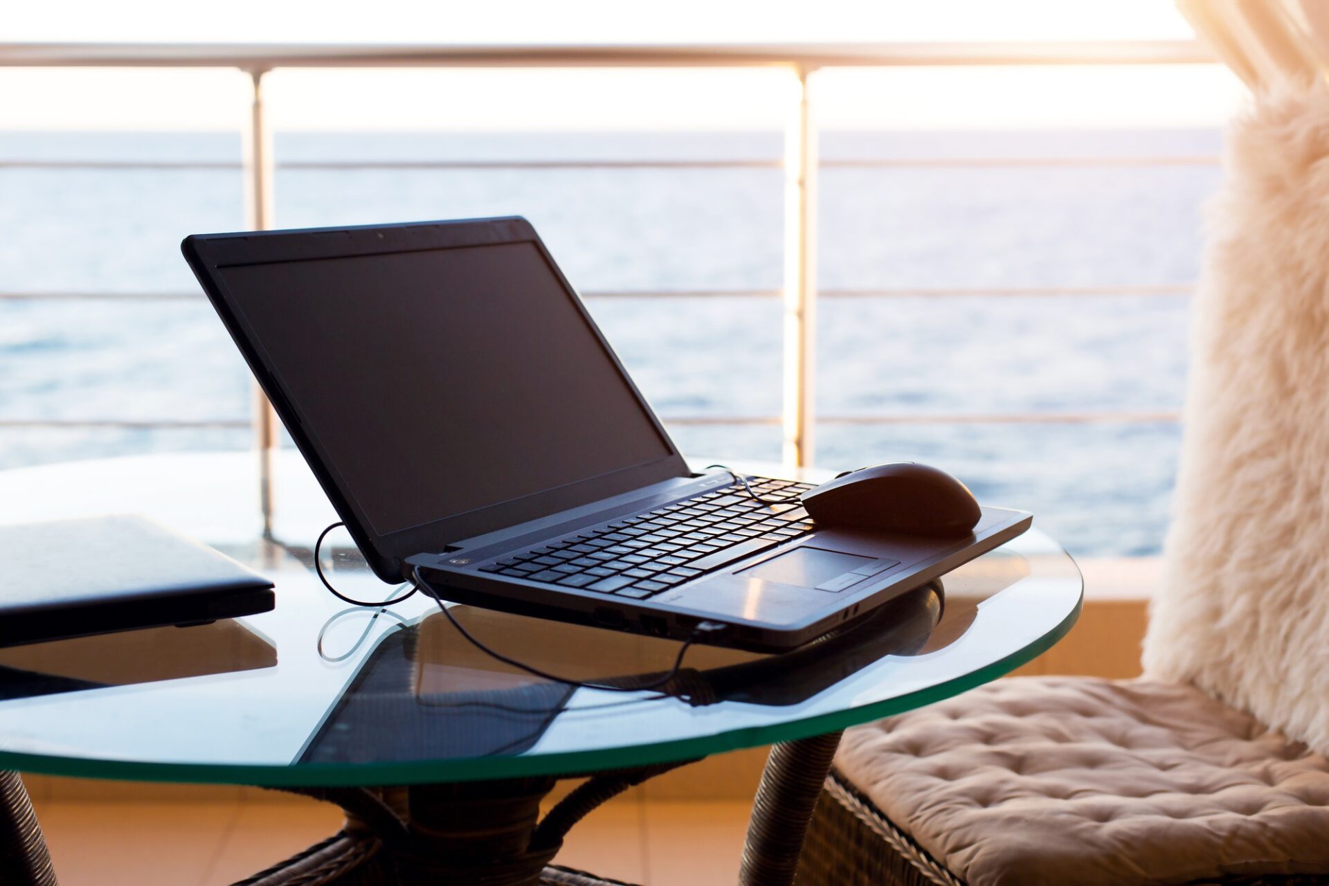 Laptop on the table on the hotel balcony with sea view. Remote work, doing business