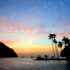 Tropical Caribbean pastel sunset silhouette of boats palm trees against colorful sky St Lucia island